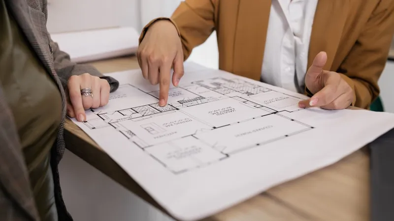 Two people pointing at a building floor plan while planning a layout